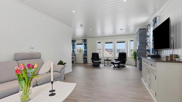 Fra stuekroken mot plass for sittegruppe ved den dekorative og stilige gasspeisen som gir lun varme på kalde dager