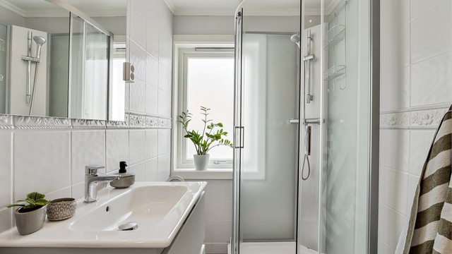 Badet er innredet med dusjkabinett, servantinnredning og speil med belysning. Varmekabler i gulv for økt komfort.