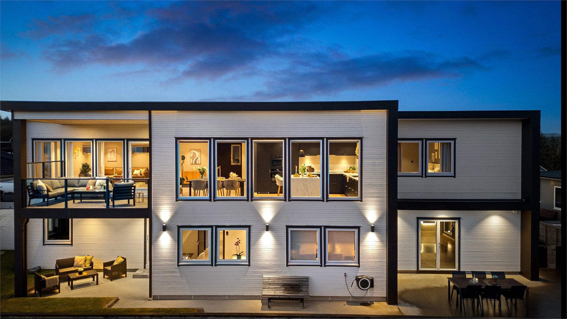 Stor flott markterrasse i finstøpt betongdekke langs store deler av husets fasade mot vest.