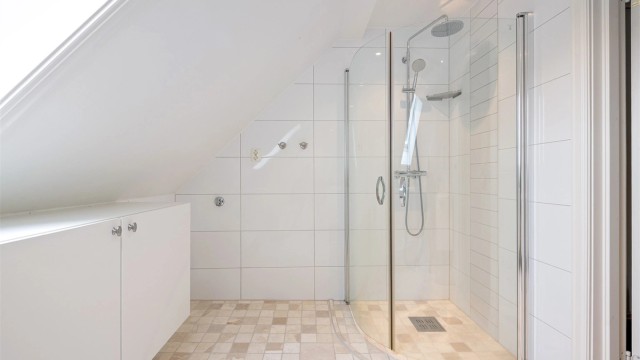 Dusjhjørne med foldbare glassvegger på bad i loftsetasjen