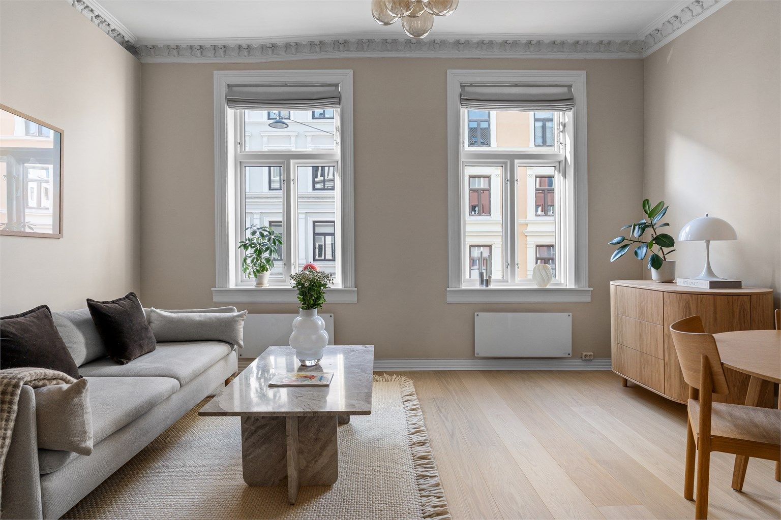 Den romslige stuen er et lyst og luftig oppholdsrom, preget av en imponerende takhøyde på ca. 3,00 meter, elegant stukkatur og rosett i himlingen.