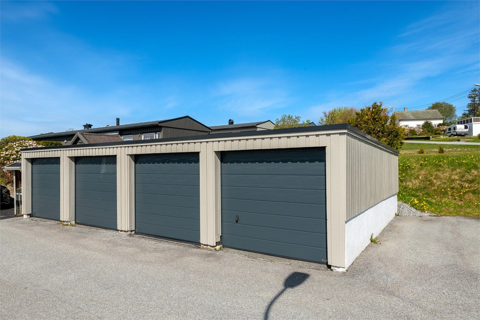 Garasjeplass i felles anlegg med ny leddport i metall og nylig installert ladepunkt for elbil