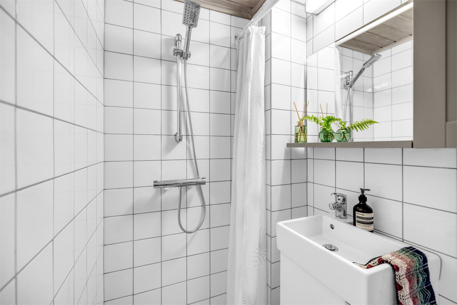Gulv belagt med fliser og gulvvarme, samt flislagte vegger som gir et helhetlig og tidløst uttrykk.