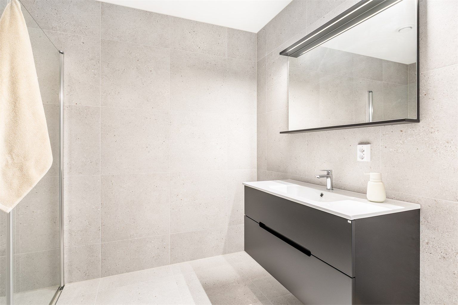 Store terrazzofliser av 60x60 cm. format på både gulvet og veggene gir badet helhet og aktualitet.