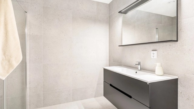 Store terrazzofliser av 60x60 cm. format på både gulvet og veggene gir badet helhet og aktualitet.
