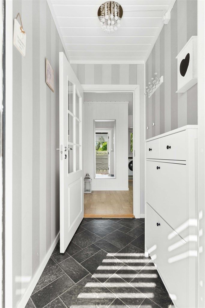 Lys og innbydende entré med moderne fliser og delikat tapet.