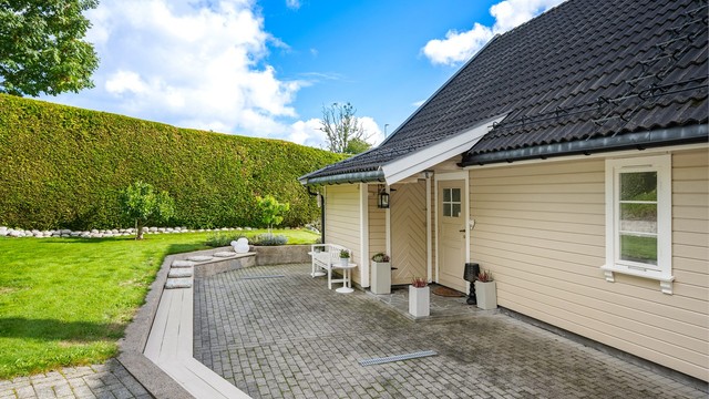 Overbygd inngangsparti med belegningsstein og skjermet sitteplass.