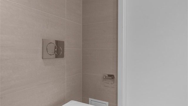 Badet har vegghengt toalett og et plassbesparende dusjhjørne med innfellbare dører.