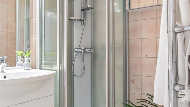 Badet har vegghengt servantinnredning, speil med overlys, dusjkabinett og gulvstående toalett, samt opplegg for vaskemaskin