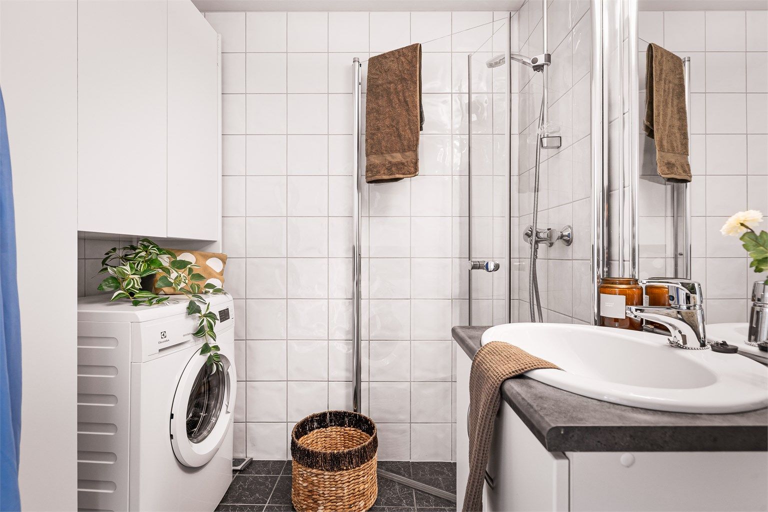Helfliset baderom med vednbare fusjvegger i glass, opplegg for vaskemaskin, skap og møblement.
