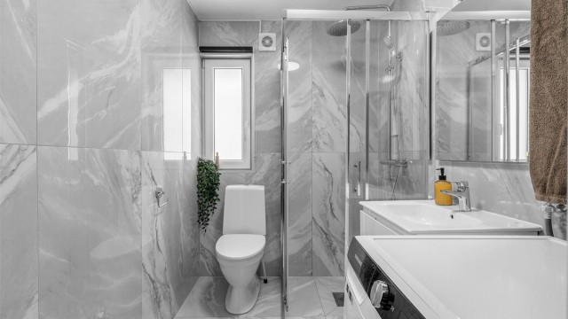 Rommet er innredet med toalett, dusjhjørne med skyvedører i glass og vegghengt servantskap med skuffer og ovenpåliggende servant med ettgreps armatur.