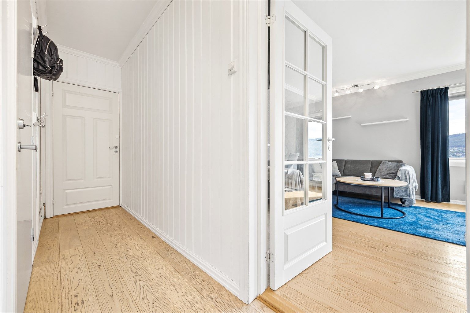 Fra entréen er det adkomst til stuen via en dør med glassfelt som slipper inn lys.