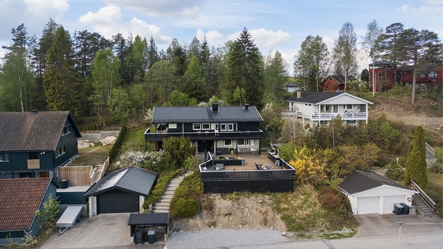 Eiendommen ligger i skrånende terreng med opparbeidet hage og plenarealer.