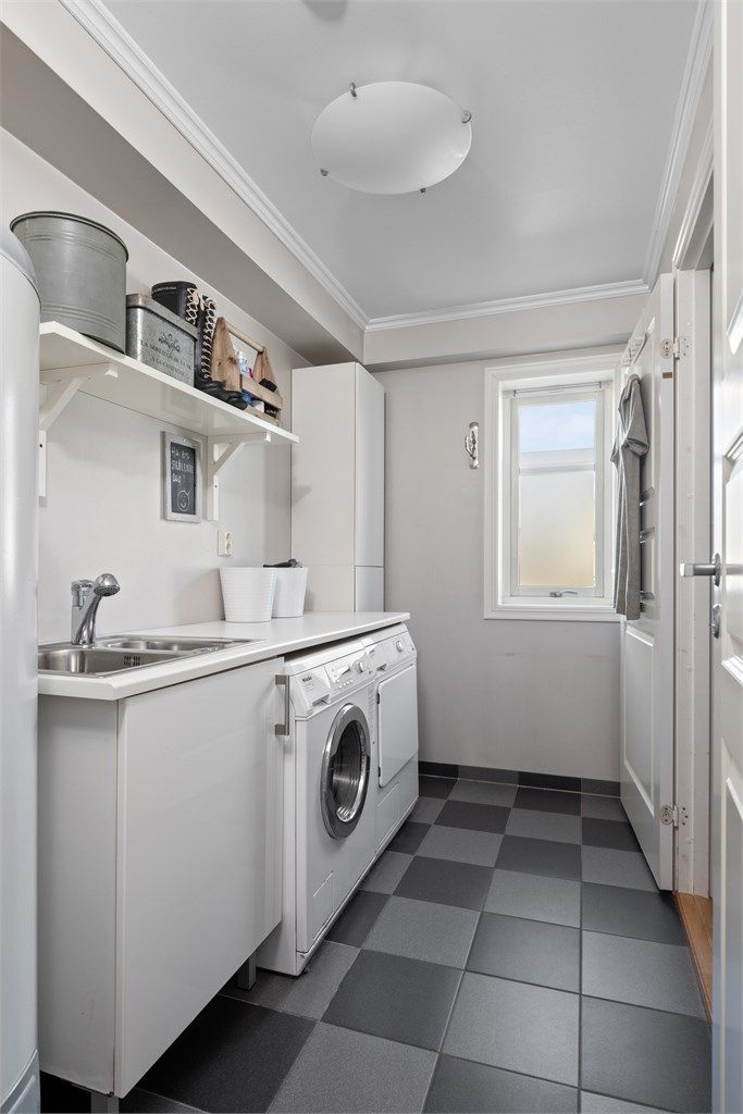 Vaskerommet har flislagt gulv med varme, og i rommet er det etablert et benkeskap med dobbel utslagsvask og tilhørende høyskap.