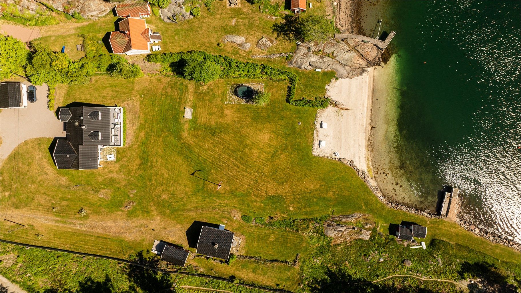 Tomten sett ovenfra, med strandlinje og bryggeanlegg.