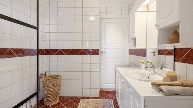 Flislagt bad med vegghengt servantinnredning og opplegg for vaskemaskin.