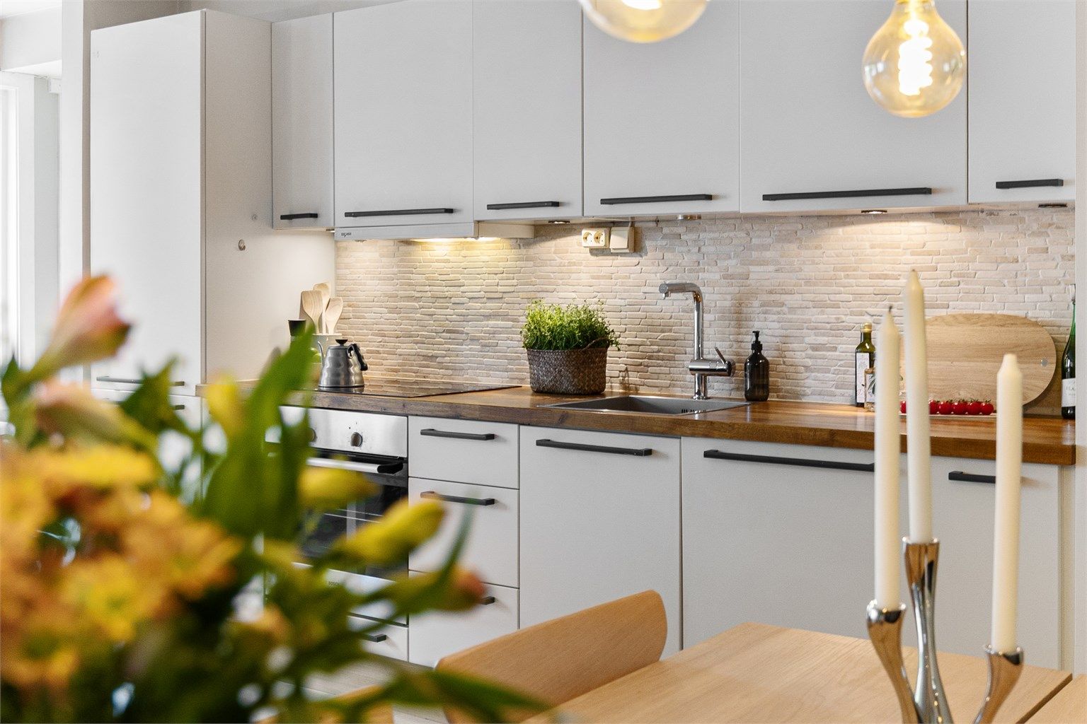 Detalj fra kjøkkenet, som har flislagt vegg mellom benkeplate og overskap.