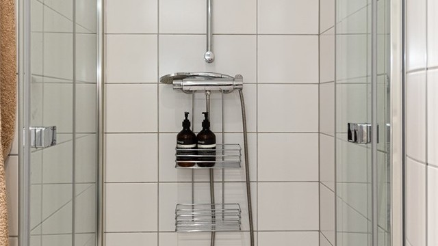Dusjhjørne med innfellbare glassdører og flislagte vegger.