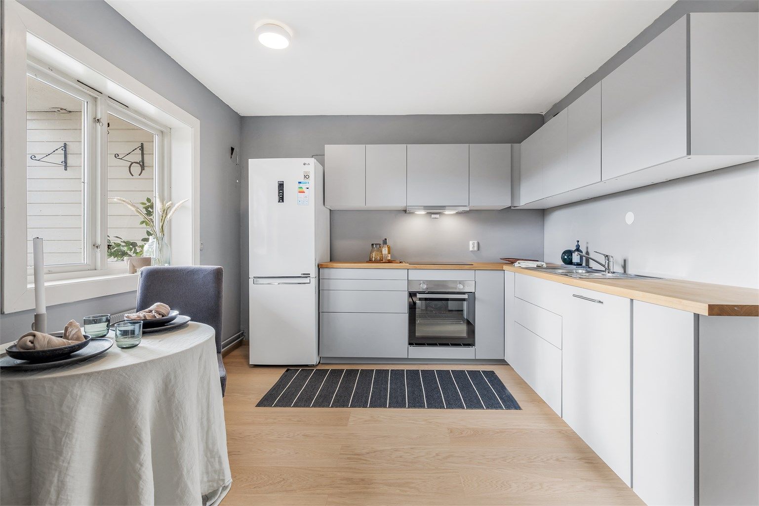 Nyoppusset kjøkken med delvis integrerte hvitevarer og plass til mindre spisebord.