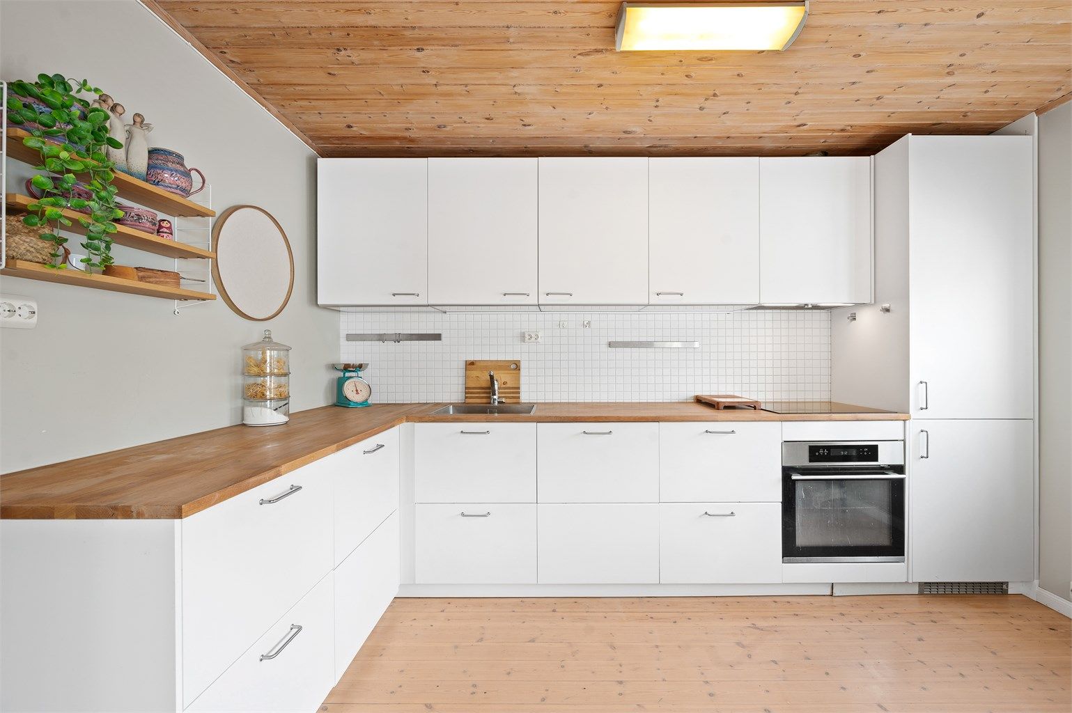 Kjøkkeninnredning fra 2019 med glatte fronter, integrerte hvitevarer og benkeplate i tre.