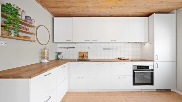 Kjøkkeninnredning fra 2019 med glatte fronter, integrerte hvitevarer og benkeplate i tre.