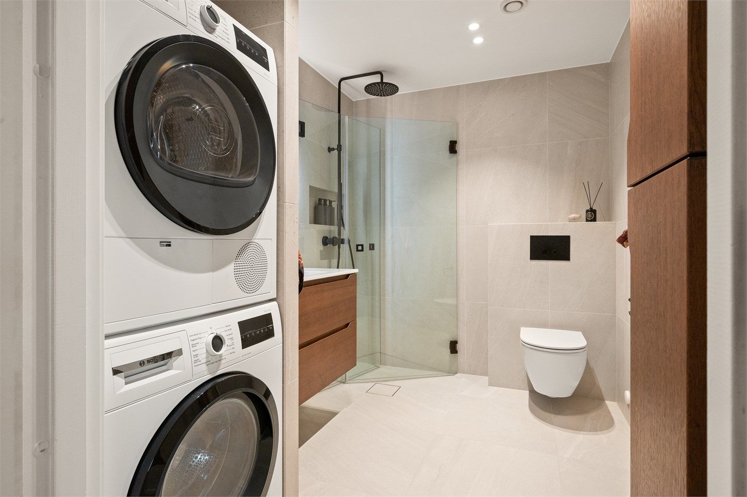 Her er det vegghengt klosett, dusjhjørne med svingbare glassdører og opplegg for vaskesøyle.