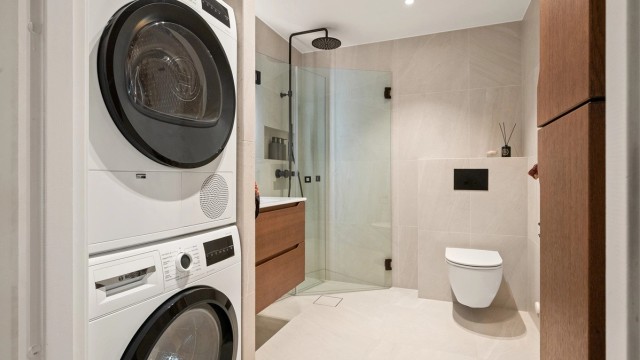 Her er det vegghengt klosett, dusjhjørne med svingbare glassdører og opplegg for vaskesøyle.