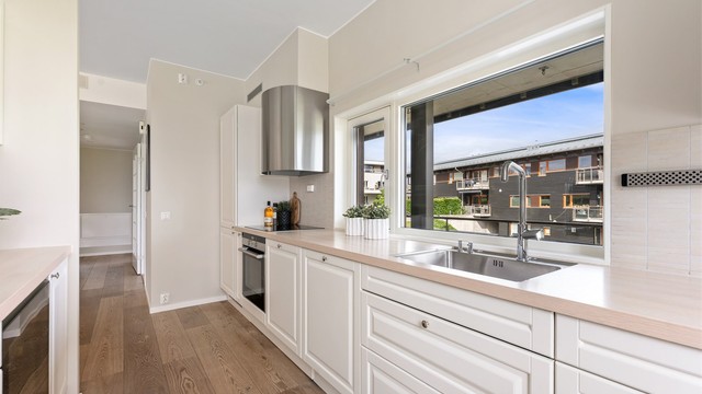 Kjøkkenet har profilerte fronter på skap og skuffer, og benkeplate med laminert overflate