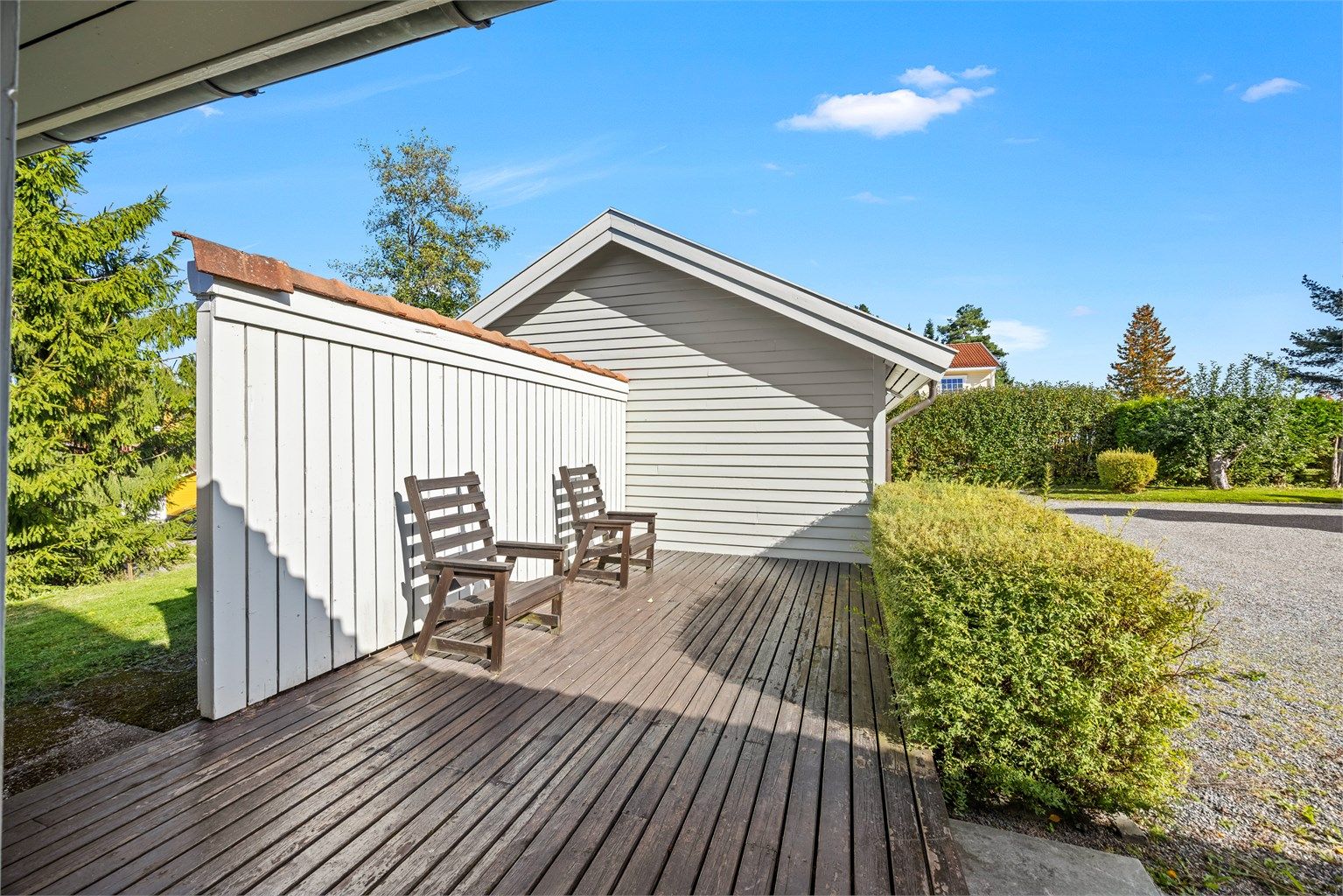 Åpen terrasse med spaltegulv i impregnert treverk og skjermende levegg.