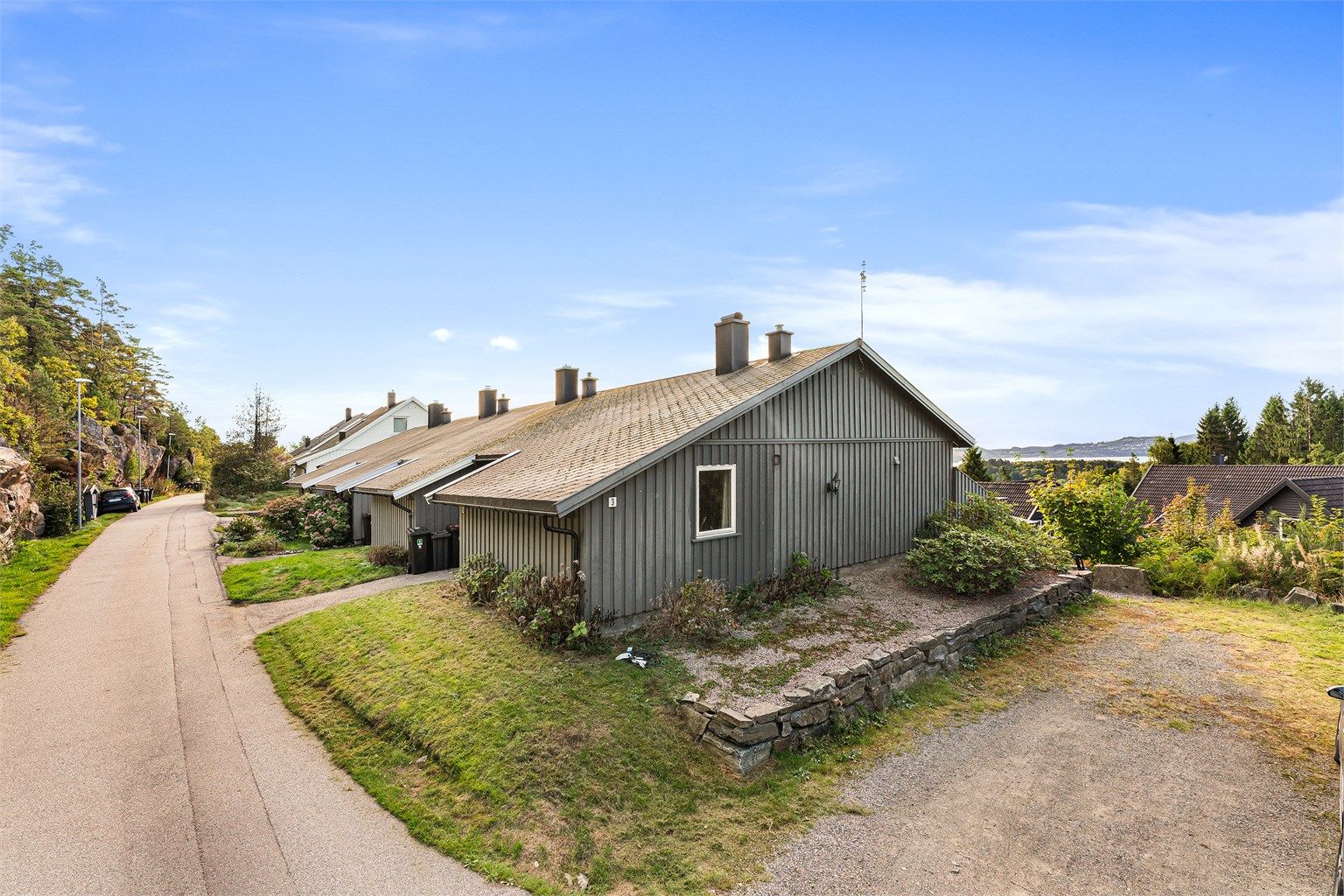 Det er hyggelig grøntareal rundt og foran boligen. Til høyre har nåværende eier parkert sine biler (se pkt. parkering).