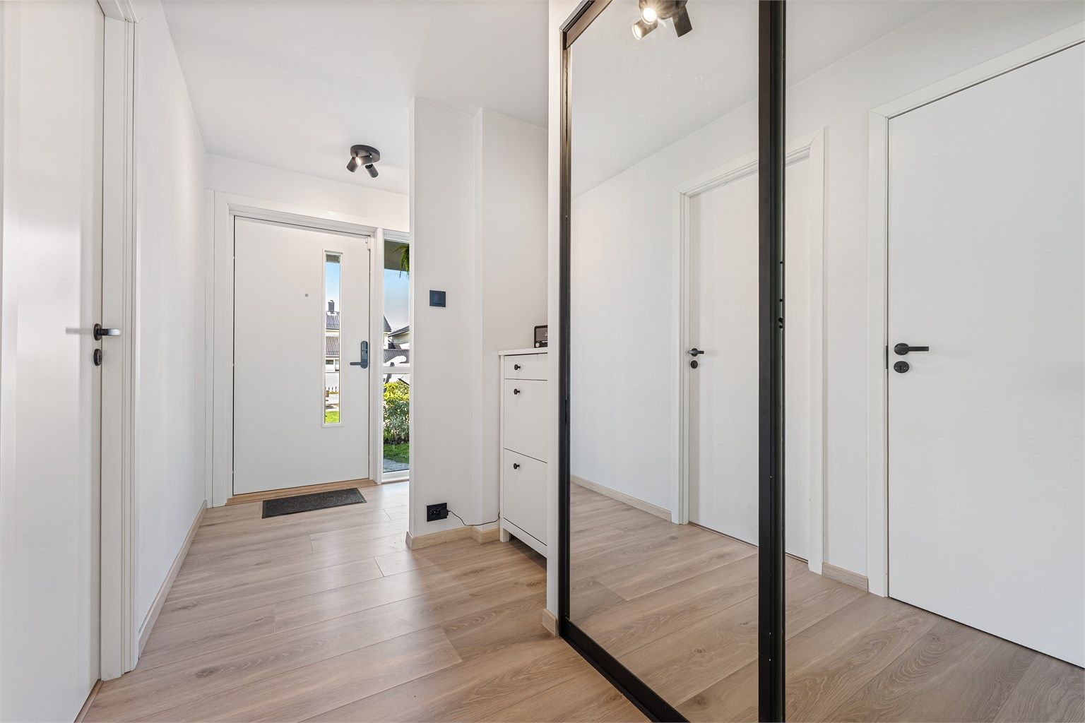 Entré med laminat på gulv, lyse vegger og himling. Plass til å henge av yttertøy i skyvedører med speilfronter. 