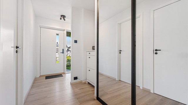 Entré med laminat på gulv, lyse vegger og himling. Plass til å henge av yttertøy i skyvedører med speilfronter.