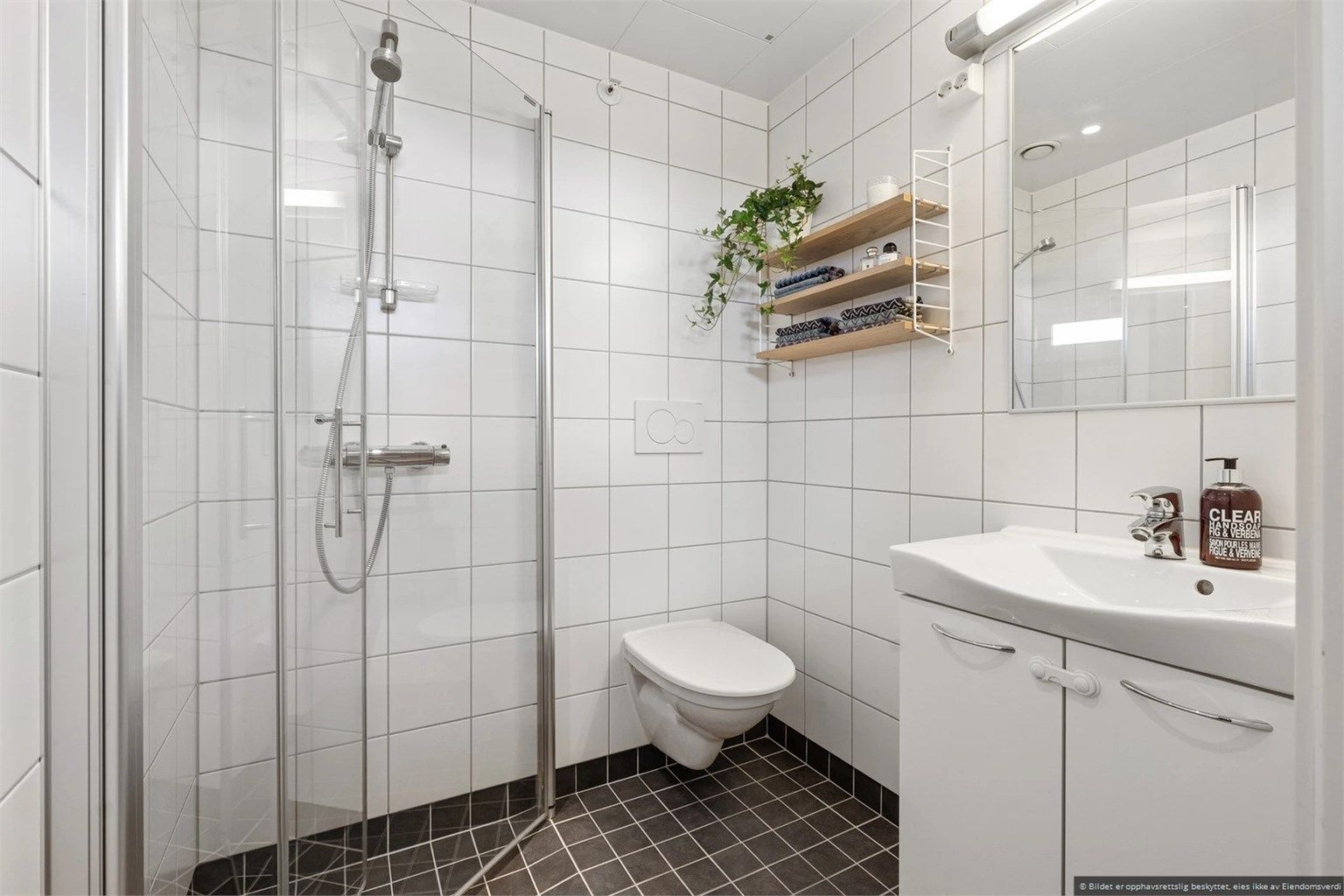 Ved entreen finner du en praktisk og pent flislagt bad med innfellbare dusjdører. 