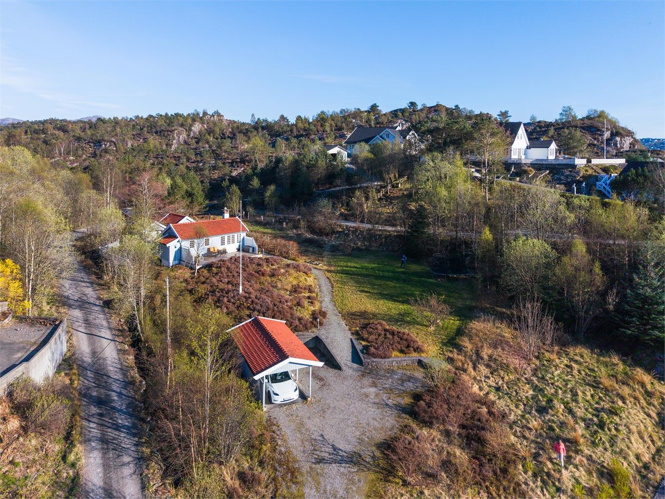 Det er gode parkeringsmuligheter på tomten med både carport, parkeringsplass på grus og parkeringsplass bak anneksene.