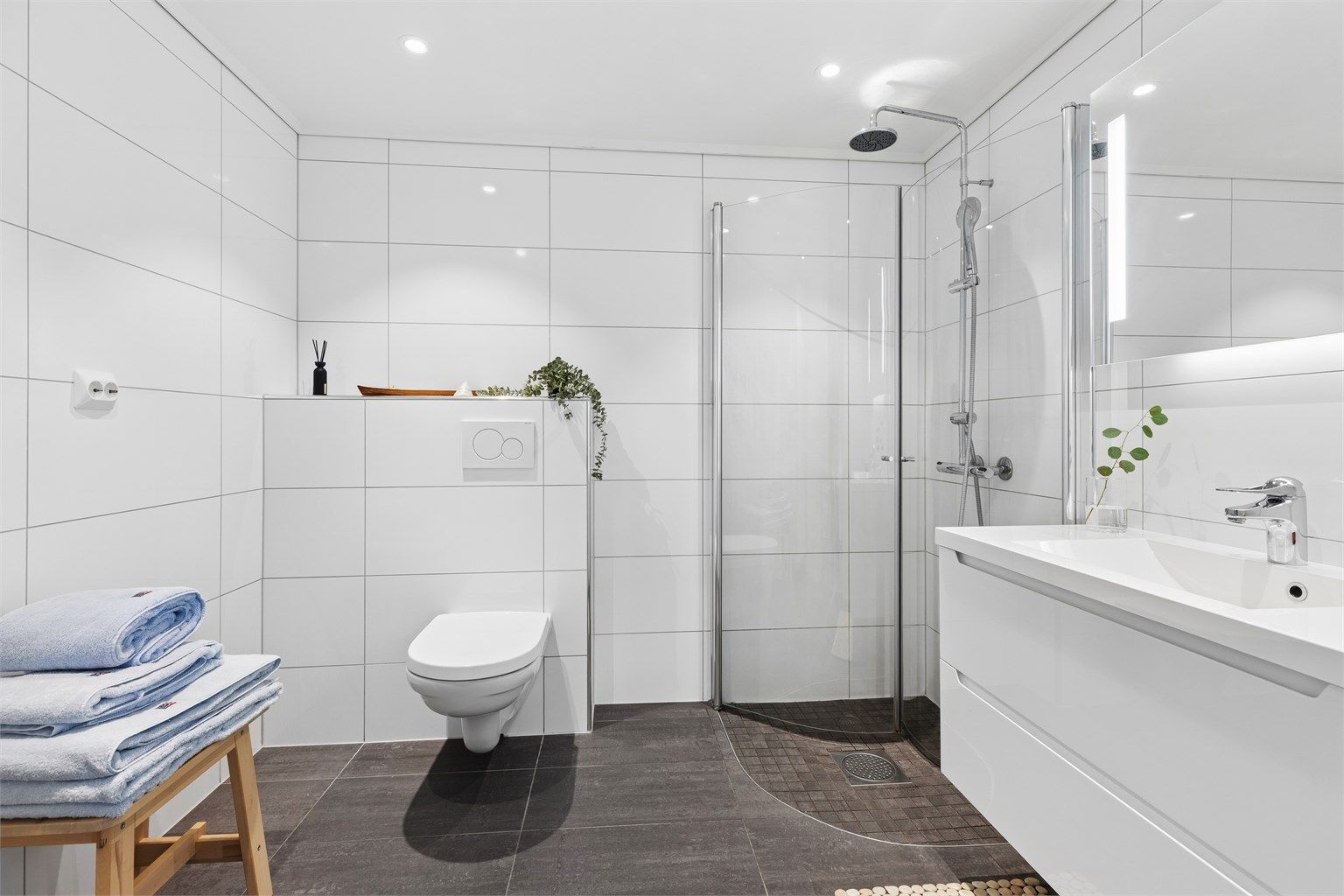 Badet i 1.etg har moderne lekre fliser, gulvvarme, vegghengt toalett og servantskap med god plass samt dusjhjørnet med praktiske innfellbare dører.