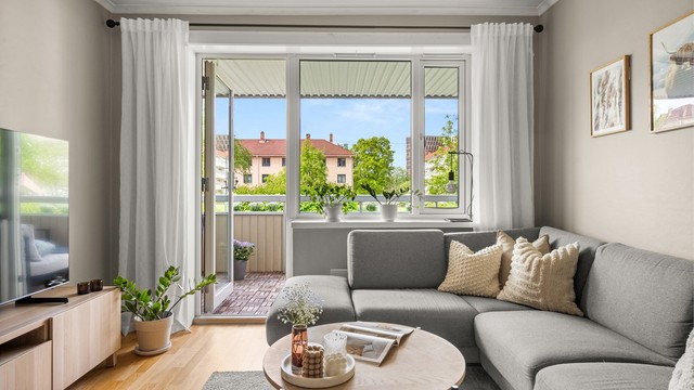 Store vindusflater og balkongdør fra 2018 slipper inn dagslys i stuen.