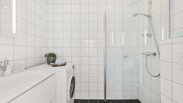 Bad med vannbåren gulvvarme og downlights i himling. Opplegg for vaskemaskin