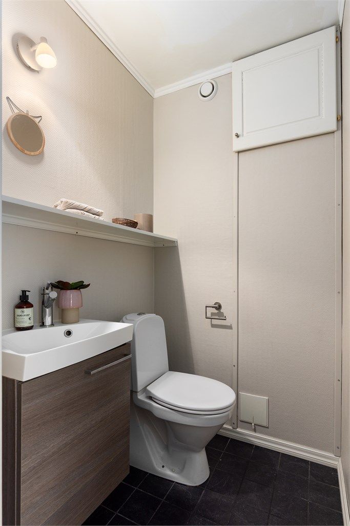 Separat toalettrom med wc, servant med underskap. Varmtvannsberederen er plassert bak veggen ved luken på bildet.
