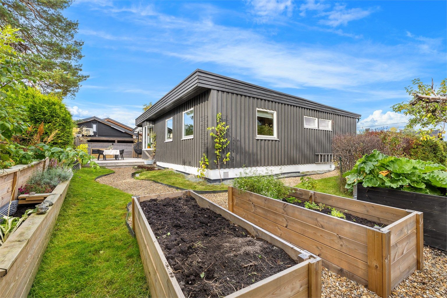 Hagen er opparbeidet med plantekasser, grusganger og plenareal.