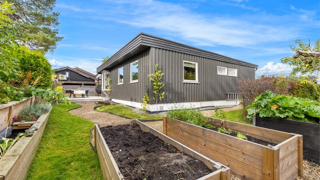 Hagen er opparbeidet med plantekasser, grusganger og plenareal.
