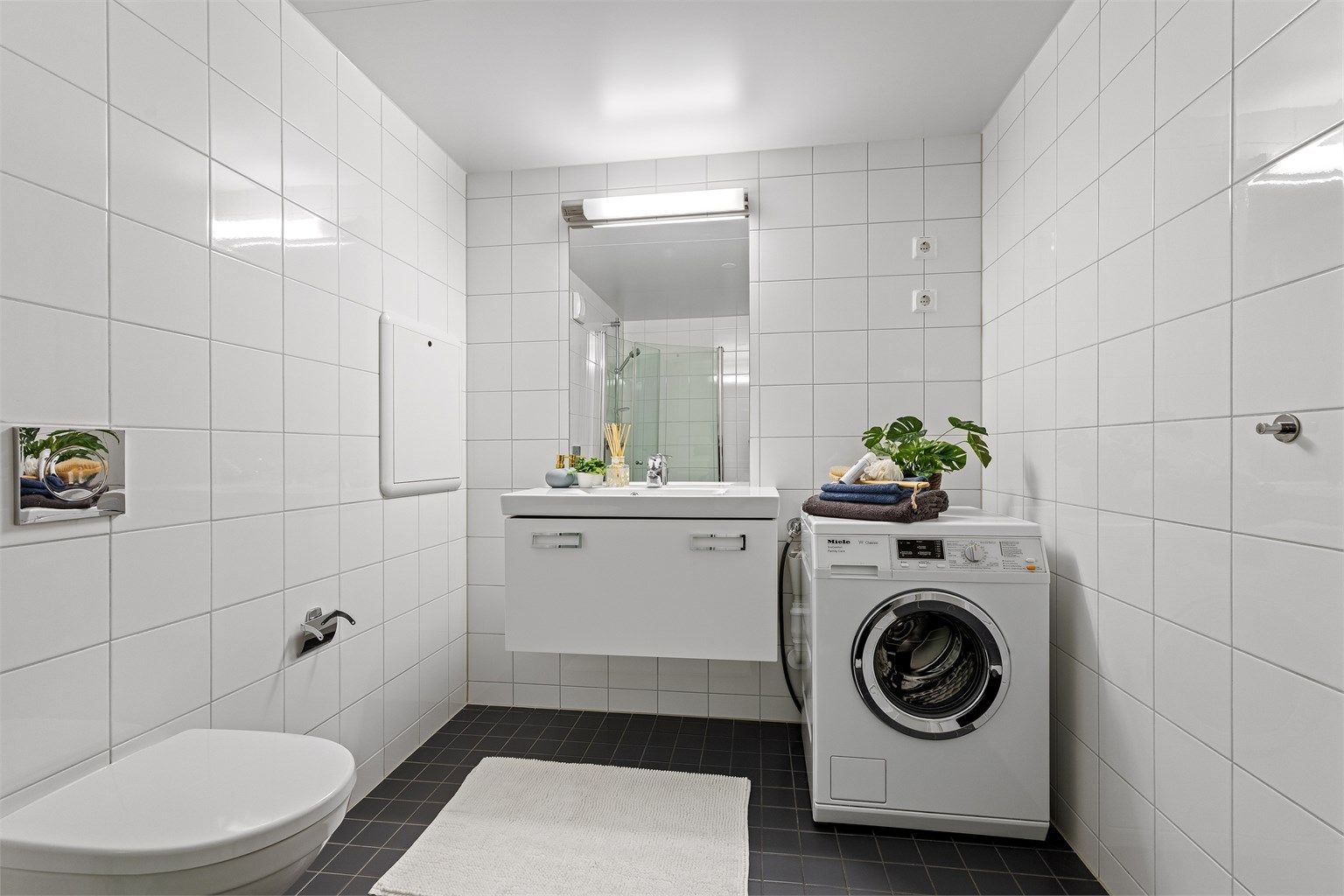 Badet har servantinnredning, speil med overlys og opplegg for vaskemaskin.
