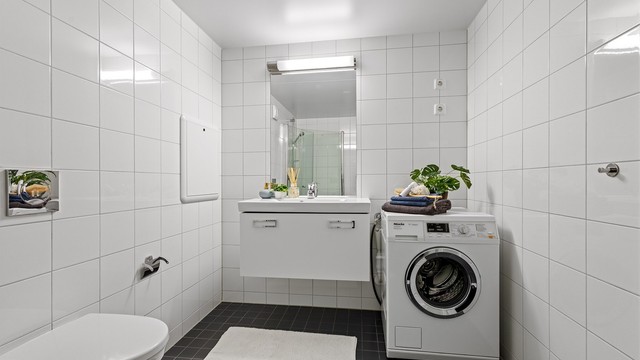 Badet har servantinnredning, speil med overlys og opplegg for vaskemaskin.