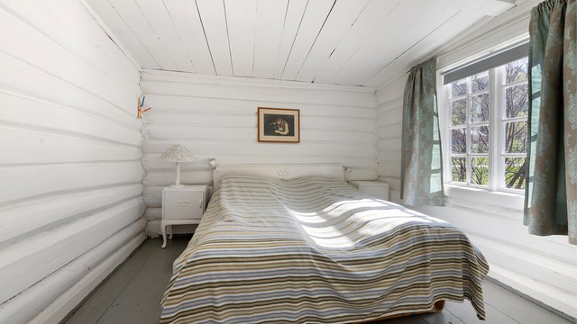 Et av tre soverom i hovedhusets andre etasje, med malte tømmervegger som bevarer bygningens karakter.
