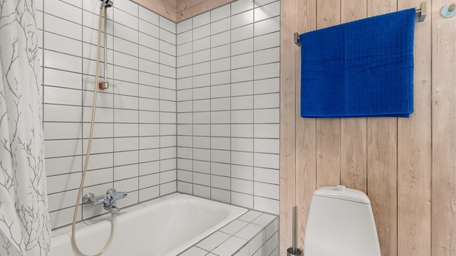 Badet i første etasje har flislagt gulv med gulvvarme og innebygget badekar.