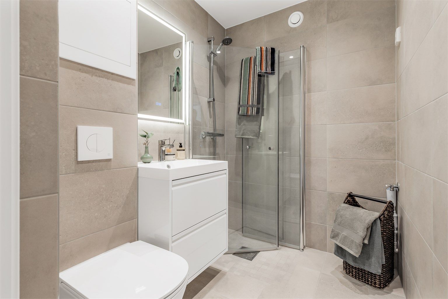 Bad fra 2024. Flislagt gulv med gulvvarme og flislagte vegger. Malt himlingsflate med downlights. Servant med ett-greps armatur og speil. Dusjhjørne med dusjarmatur.