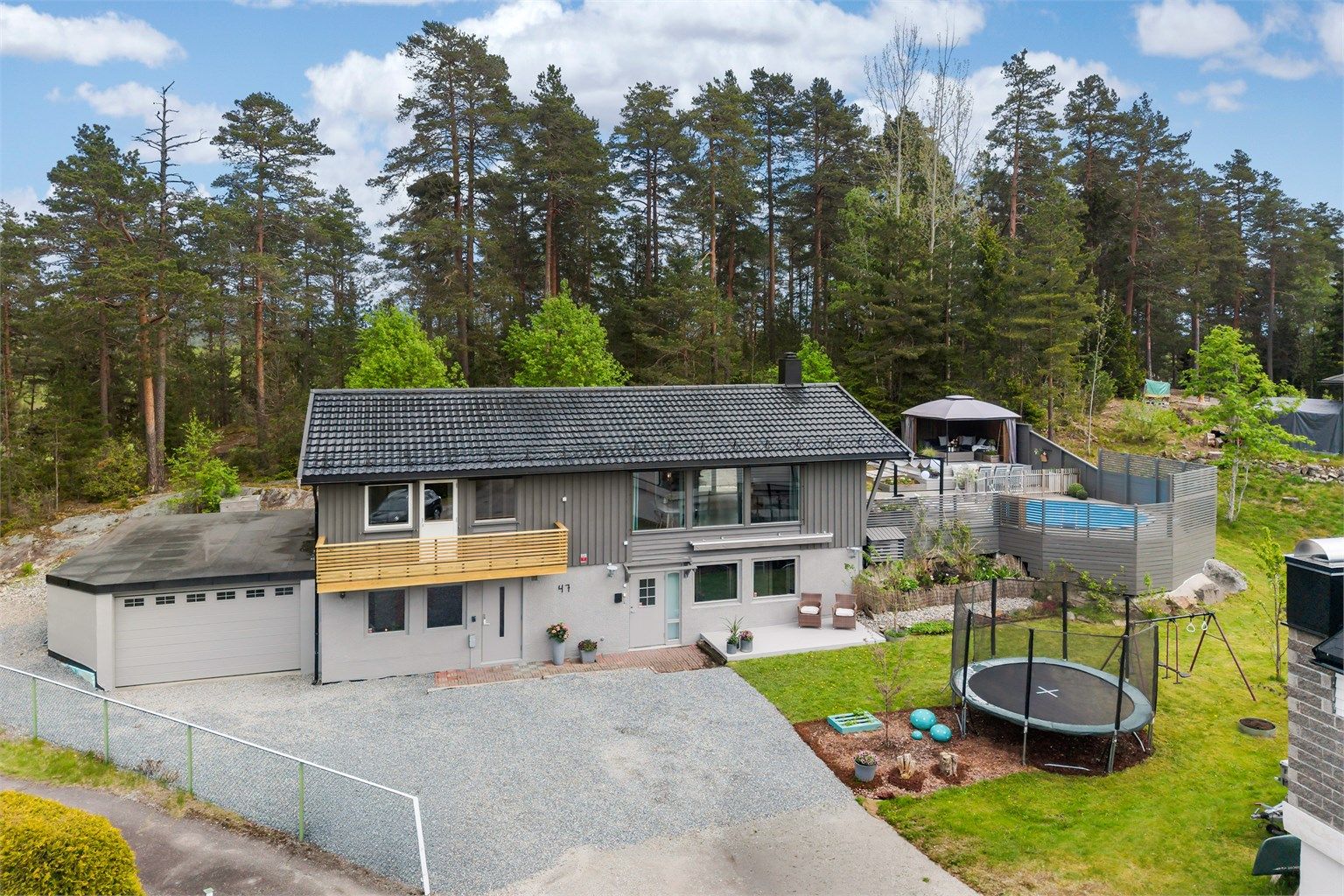 Romslig, singelbelagt gårdsplass med tilliggende garasje + bod. Elbillader er montert på husvegg. 