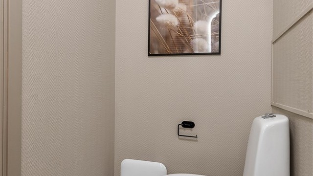 Toalettrom med tilgang fra badet og entreen. Gulvflate belagt med fliser. Tapetserte veggflater. Malte flater i himling. Vegghengt servantinnredning. Gulvstående toalett. Mekanisk avtrekk med ventil i vegg.
