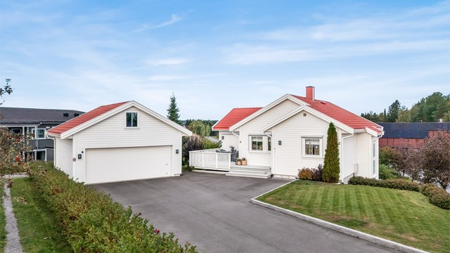 Asfaltert gårdsplass, lettstelt hage og frittstående garasje med hems.