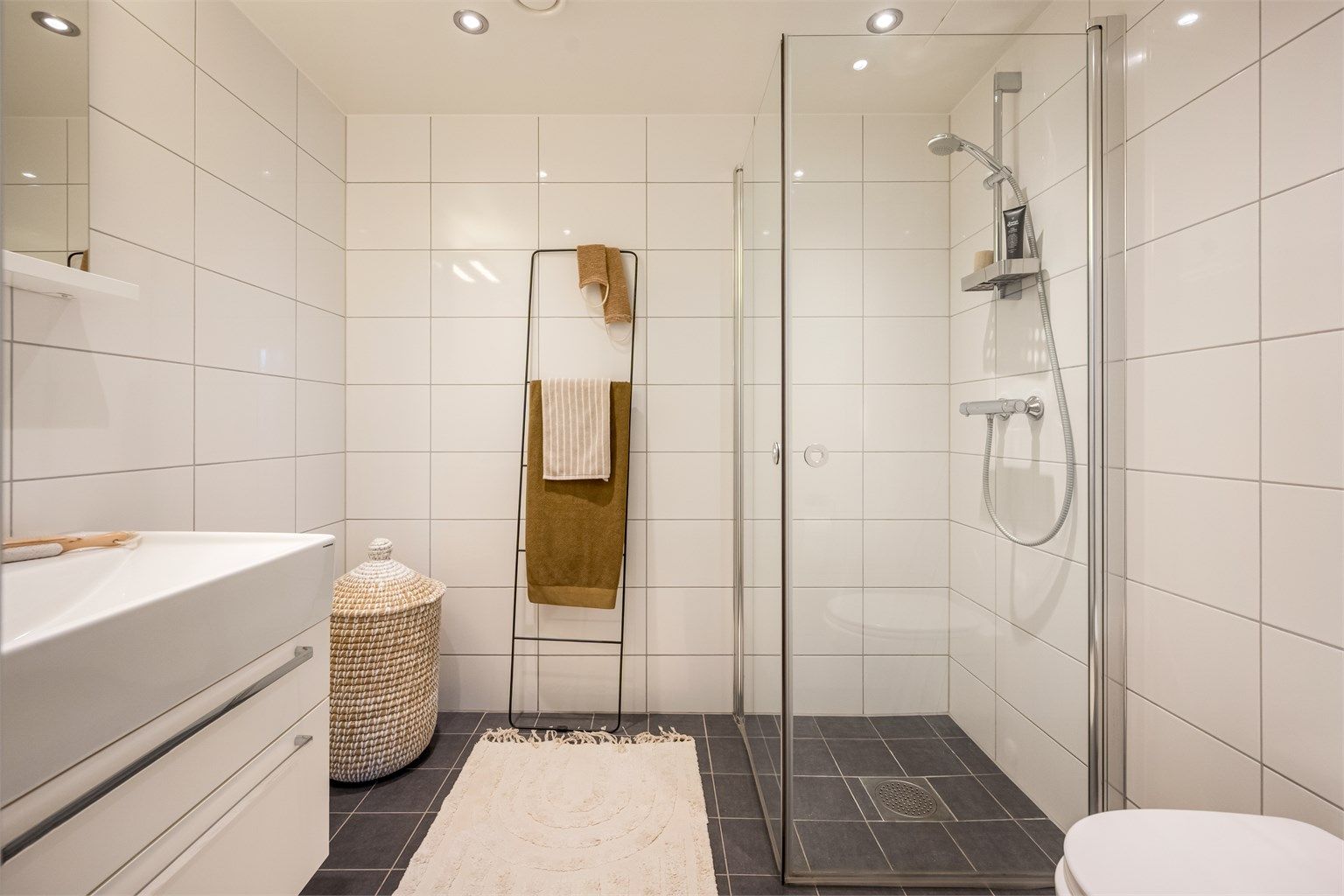 Leilighetens andre bad er også flislagt og har varmekabler i gulvet. Downlights i tak, vegghengt toalett og dusjhjørne med svingbare glassdører.