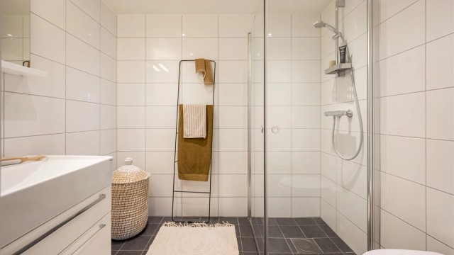 Leilighetens andre bad er også flislagt og har varmekabler i gulvet. Downlights i tak, vegghengt toalett og dusjhjørne med svingbare glassdører.